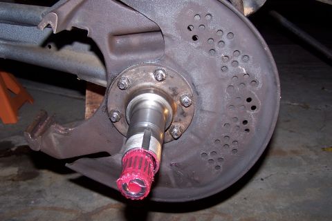 1990 Ford Bronco - Close-up of a vehicle's wheel hub and brake rotor assembly, showing greased spindle and perforated dust shield.