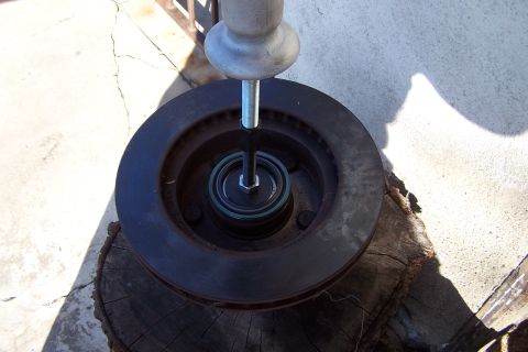 1990 Ford Bronco - A brake rotor and bearing assembly are shown with a tool pressing the bearing into place.