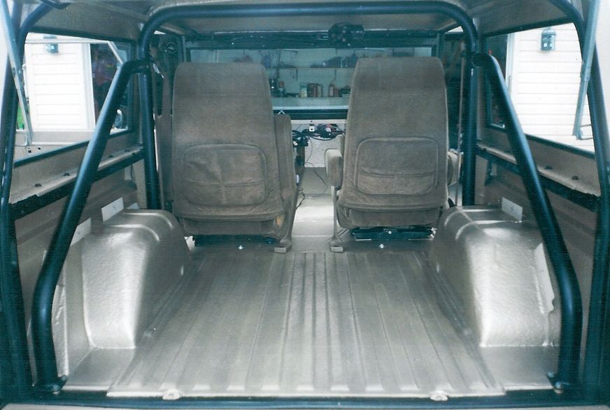 Interior of an SUV looking forward over two cloth bucket seats and a bare cargo floor