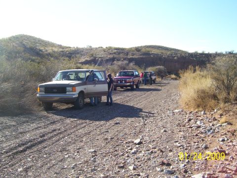 1993 Ford Bronco - A group of Ford Broncos are seen on a dirt road in a desert landscape.
