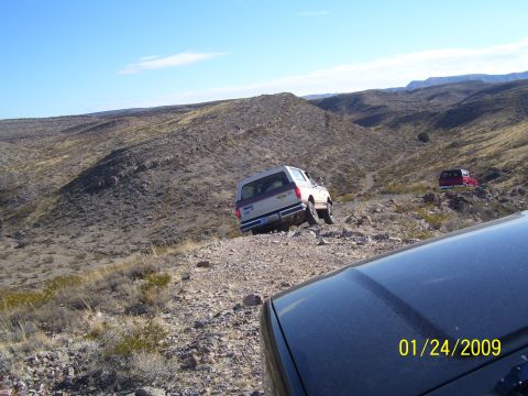 1993 Ford Bronco - Two SUVs navigate a , arid landscape under a clear blue sky.