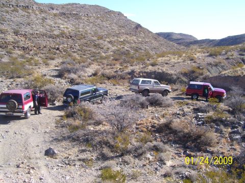 1993 Ford Bronco - Four Ford Broncos are seen parked on a dirt road in a rocky, arid environment, with mountains in the background.