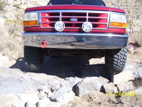 1993 Ford Bronco - Front view of a red 1993 Ford Bronco navigating a rocky trail.