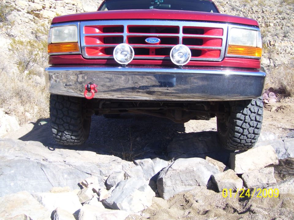 1993 Ford Bronco front end, red, with chrome bumper and tow hook, on rocky terrain