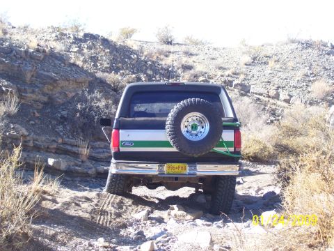 1993 Ford Bronco - A Ford Bronco navigates a rough, rocky terrain with its rear end visible.