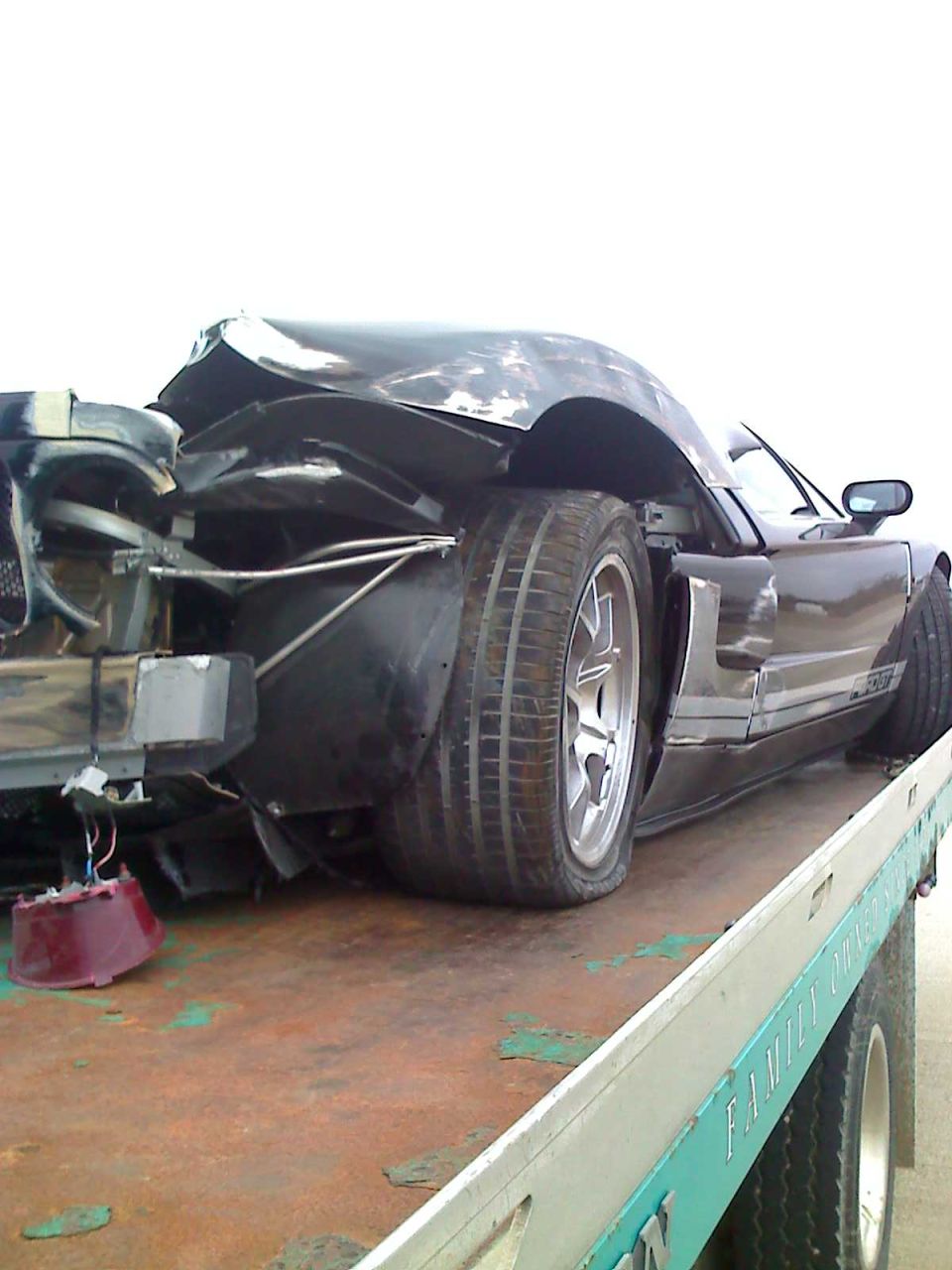 Black sports car with heavily damaged rear end on tow truck