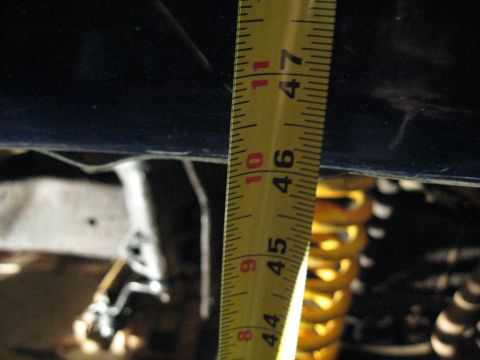 1978 Ford Bronco - Measuring suspension lift with a tape measure next to a yellow coil spring.