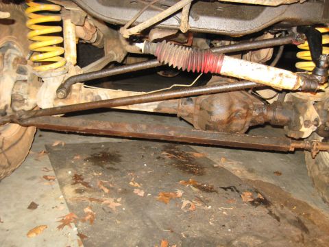 1978 Ford Bronco - Close-up view of the front axle and steering components of a vehicle, likely undergoing maintenance.