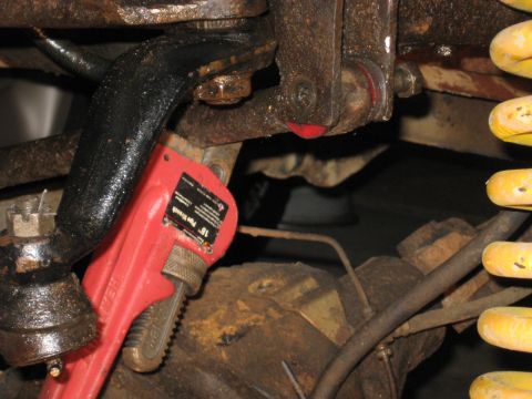 1978 Ford Bronco - A red pipe wrench is attached to a vehicle's suspension system, suggesting maintenance or repair work.