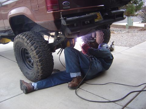 1996 Ford F-250 - A person is welding underneath a Ford Bronco II, which has been lifted with large tires.