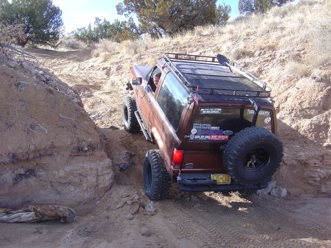 1996 Ford F-250 - A brown Ford Bronco navigates a steep, rocky incline during an off-road excursion.