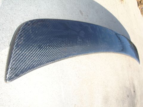 1995 Ford Taurus - A carbon fiber spoiler with a distinct woven pattern is shown resting on a concrete surface.