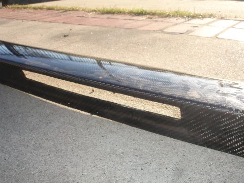 1995 Ford Taurus - Close-up of a carbon fiber part with visible weave pattern and cutouts.