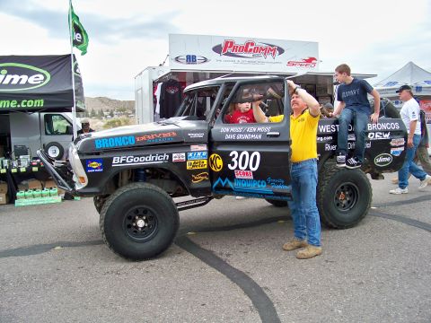 1994 Ford Bronco - A modified Ford Bronco race truck is prepared for an event, with people around it.