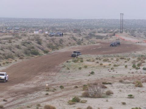 1994 Ford Bronco - Off-road vehicles compete on a dusty track in a desert environment.