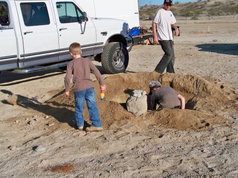1994 Ford Bronco - Children play in a dirt mound next to a white pickup truck in a desert-like environment.