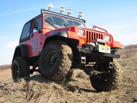 1990 Ford Bronco - This red Jeep Wrangler is equipped for off-road use with a lift kit and large tires.