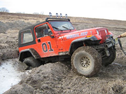 1990 Ford Bronco - This Jeep is stuck in a muddy ditch, with a winch line attached to its front bumper.