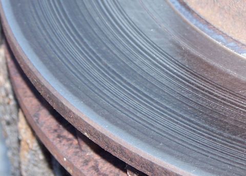 1990 Ford Bronco - This close-up shows a heavily grooved brake rotor, indicating significant wear.