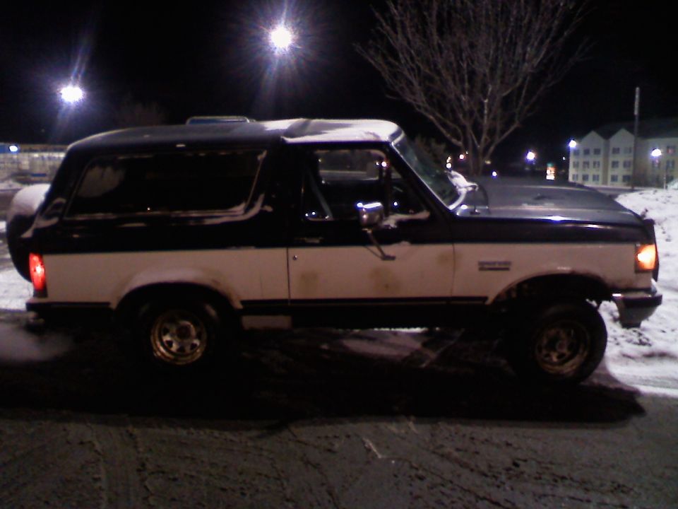 1988 Ford Bronco parked in the snow at night, side view.