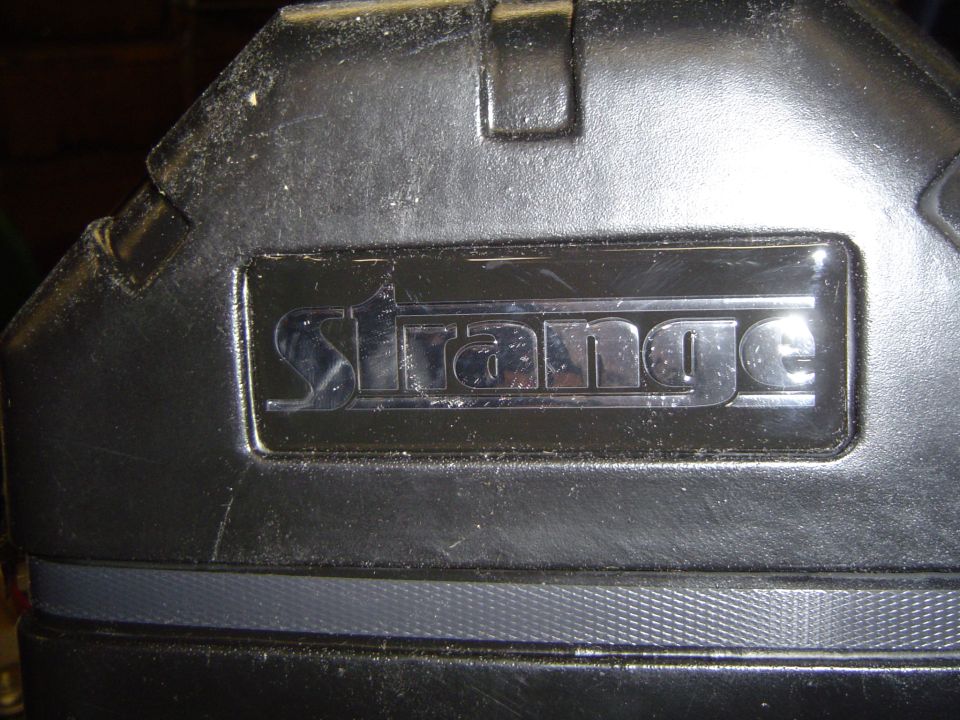 Black molded plastic case with a chrome 'Strange' emblem and top grab handle