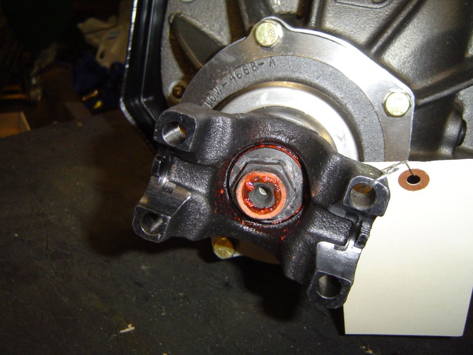 Close-up of a driveshaft U-joint with red grease around the nut. Part number 'HOW-1668-A' is visible