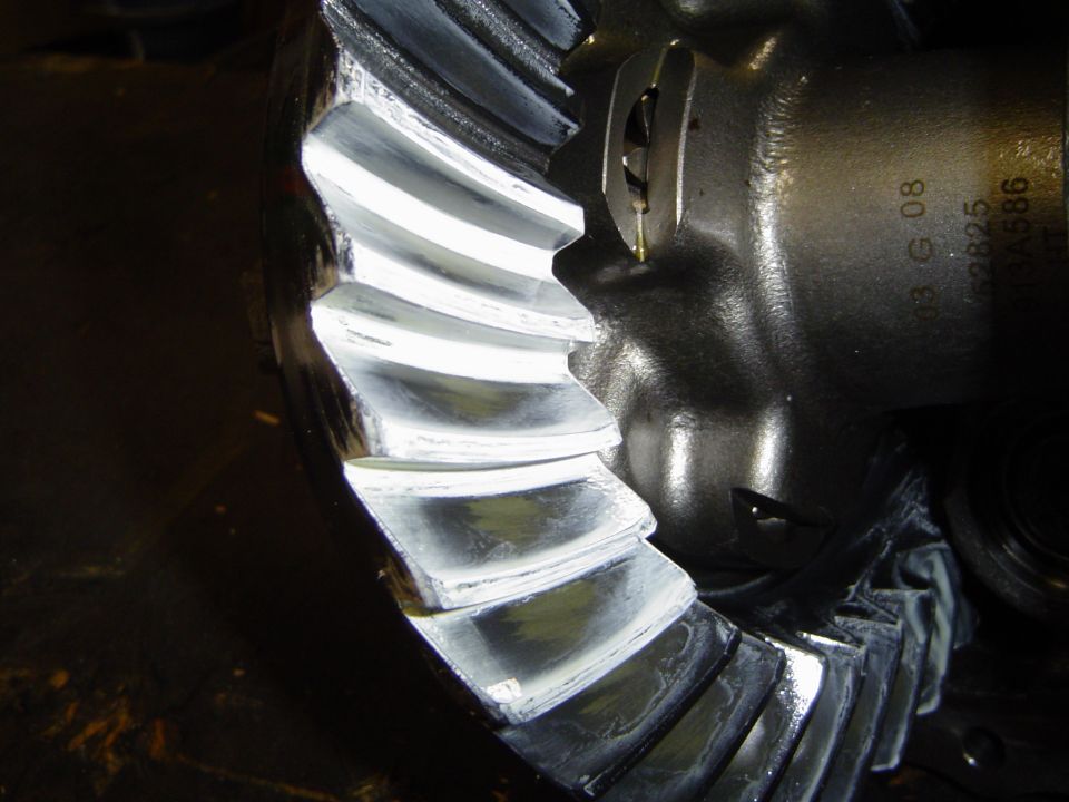 Close-up of a differential ring gear's teeth and cast carrier with stamped part numbers