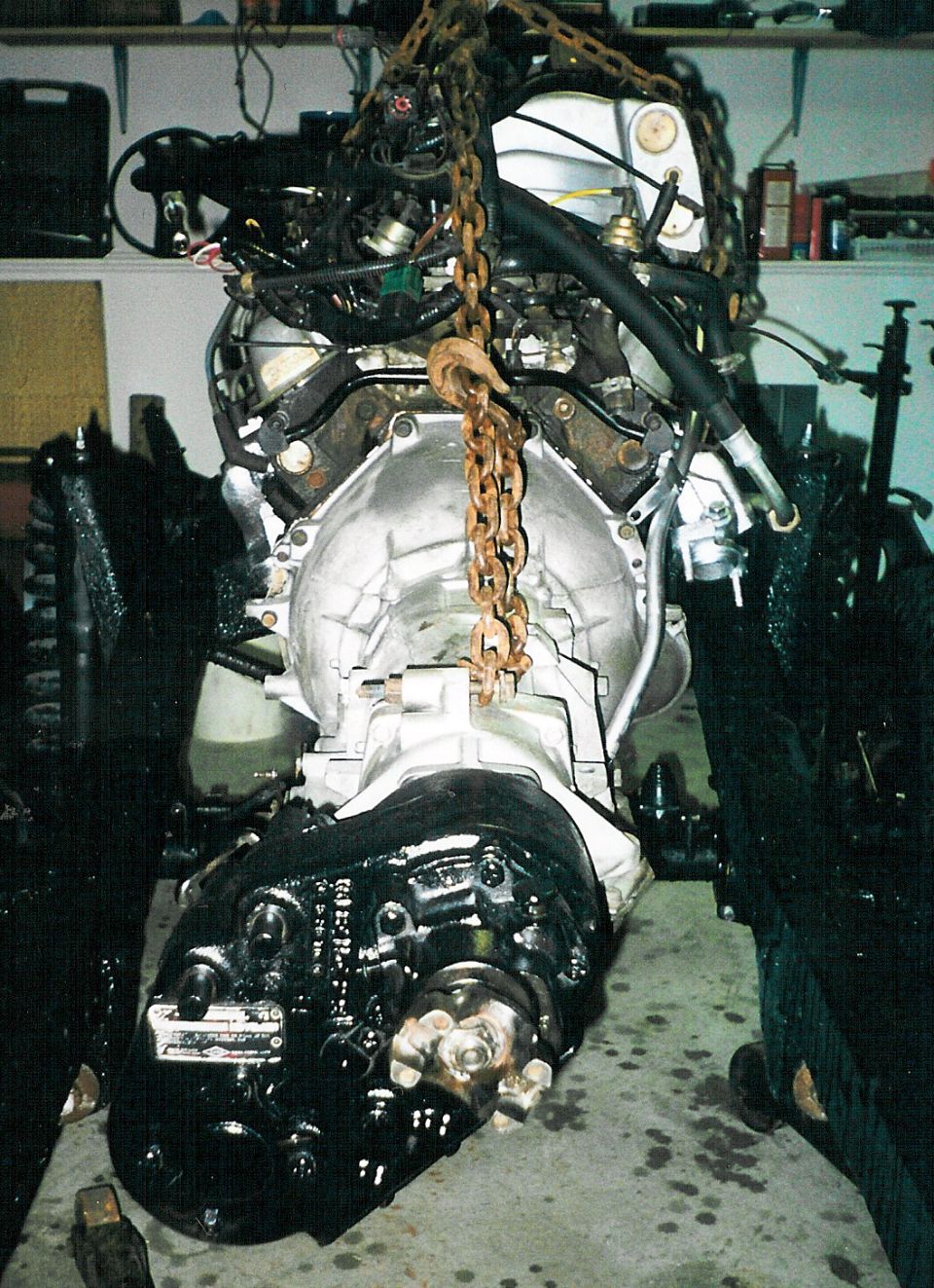 Engine and transmission with transfer case lifted by chain hoist in a garage