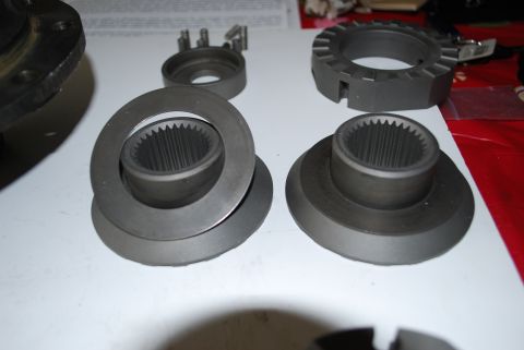 1996 Ford Bronco - Several metal automotive components are displayed on a white surface, including splined hubs and a toothed ring.