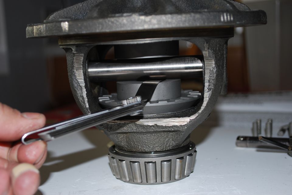 Close-up of a differential carrier with a tool measuring internal components. A bearing is visible at the bottom
