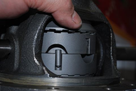 1996 Ford Bronco - A differential carrier is secured in a vise for work, with a hand pressing down on the top.