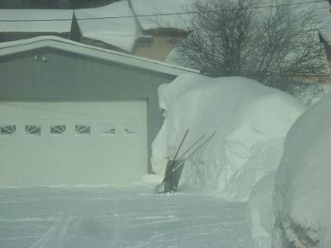 2000 Chevrolet Tahoe - A winter scene shows a garage covered in snow with shovels leaning against a large snowdrift.