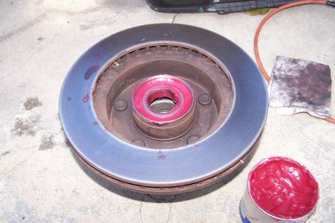 1990 Ford Bronco - A brake rotor and bearing assembly, greased and ready for installation, sits on a concrete surface.
