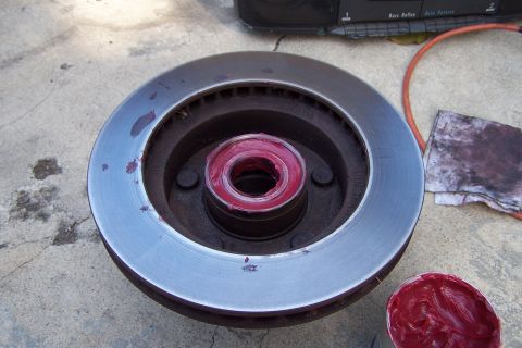 1990 Ford Bronco - A wheel bearing is packed with red grease next to a brake rotor, suggesting maintenance or repair work.