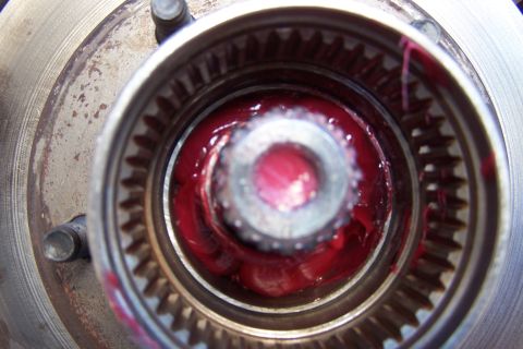 1990 Ford Bronco - Close-up view of a wheel hub assembly filled with red grease, likely for maintenance or repair.