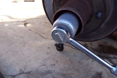 1990 Ford Bronco - A socket wrench is used to work on a vehicle's hub assembly, likely for a ball joint replacement.