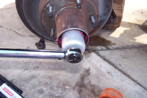 1990 Ford Bronco - Torque wrench is used to apply grease to a wheel hub assembly during maintenance.