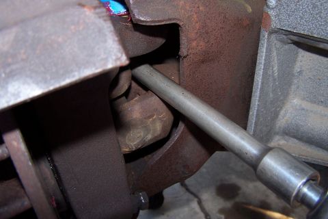 1990 Ford Bronco - A tool is being used on a vehicle's suspension system, focusing on a specific part.