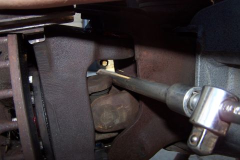 1990 Ford Bronco - Mechanic works on a vehicle's suspension system, focusing on a ball joint area.