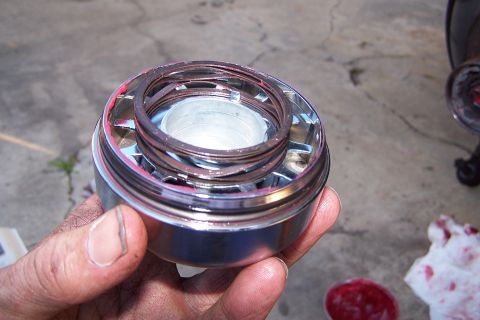 1990 Ford Bronco - A greased ball joint assembly is held in a hand, with a rag and tub of grease visible in the background.
