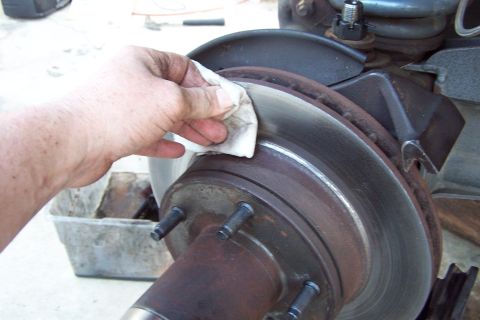 1990 Ford Bronco - A hand wipes down a brake rotor, likely as part of maintenance or repair.