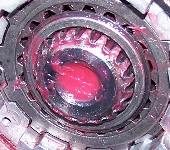 Close-up of a greased ball joint assembly with visible gears and red grease