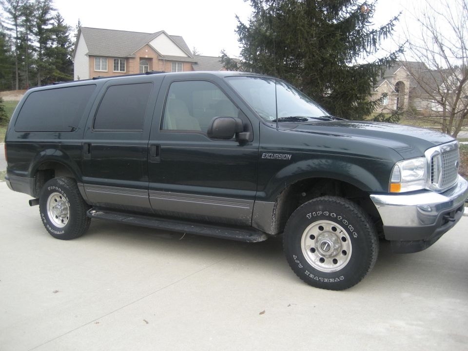 Dark green Ford Excursion parked on a driveway. The badge on the fender says 'EXCURSION'