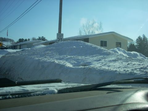 2000 Chevrolet Tahoe - A large snow pile covers most of the vehicle, with a speed limit sign indicating 35 mph visible in the background.