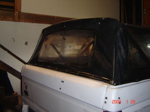 1993 Ford Bronco - Rear view of a white SUV with a black soft top, showing the interior frame through the plastic window.