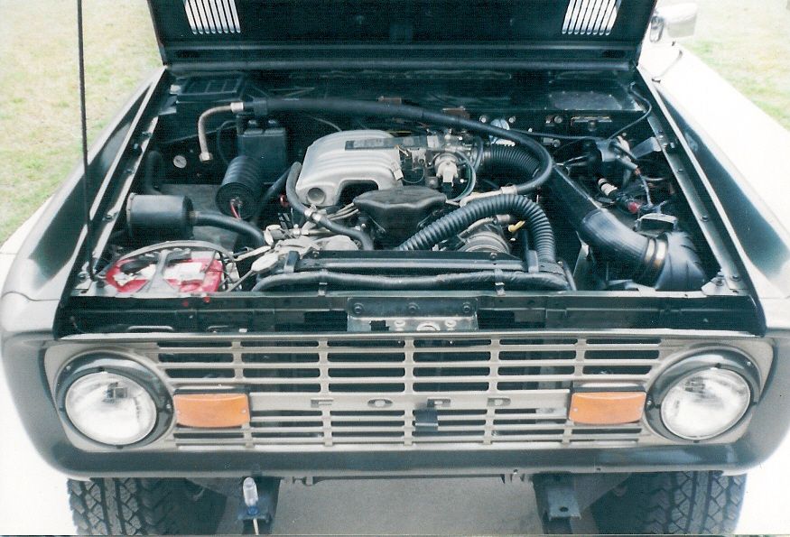 Open engine bay of early Ford Bronco showing V8 and FORD grille