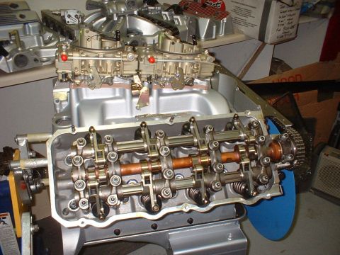 1970 Ford Mustang - The internal components of a V8 engine are visible, including the camshaft, rocker arms, and valves, with a dual carburetor setup.