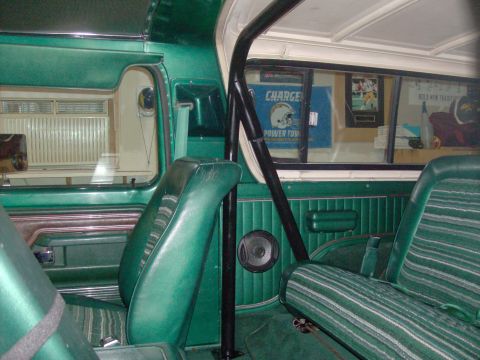1978 Ford Bronco - Interior view of a green vehicle's cabin, showing seats, a roll cage, and a speaker. A sign is visible through the rear window.