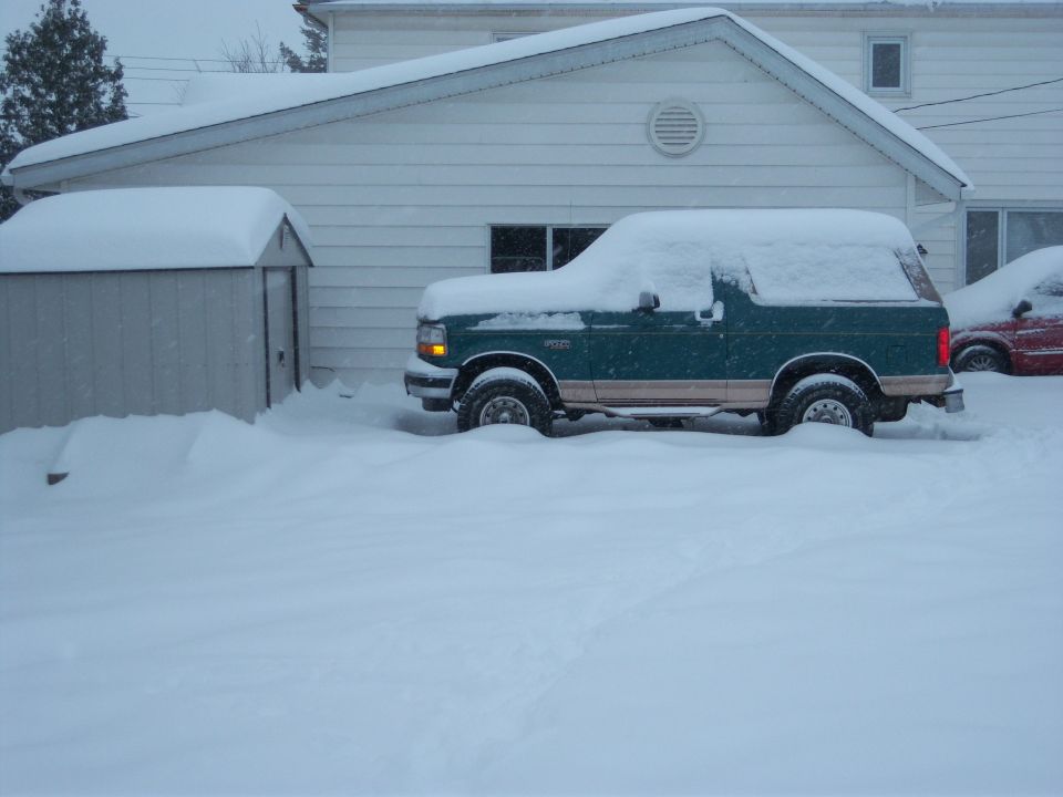 Green 1996 Ford Bronco parked in deep snow