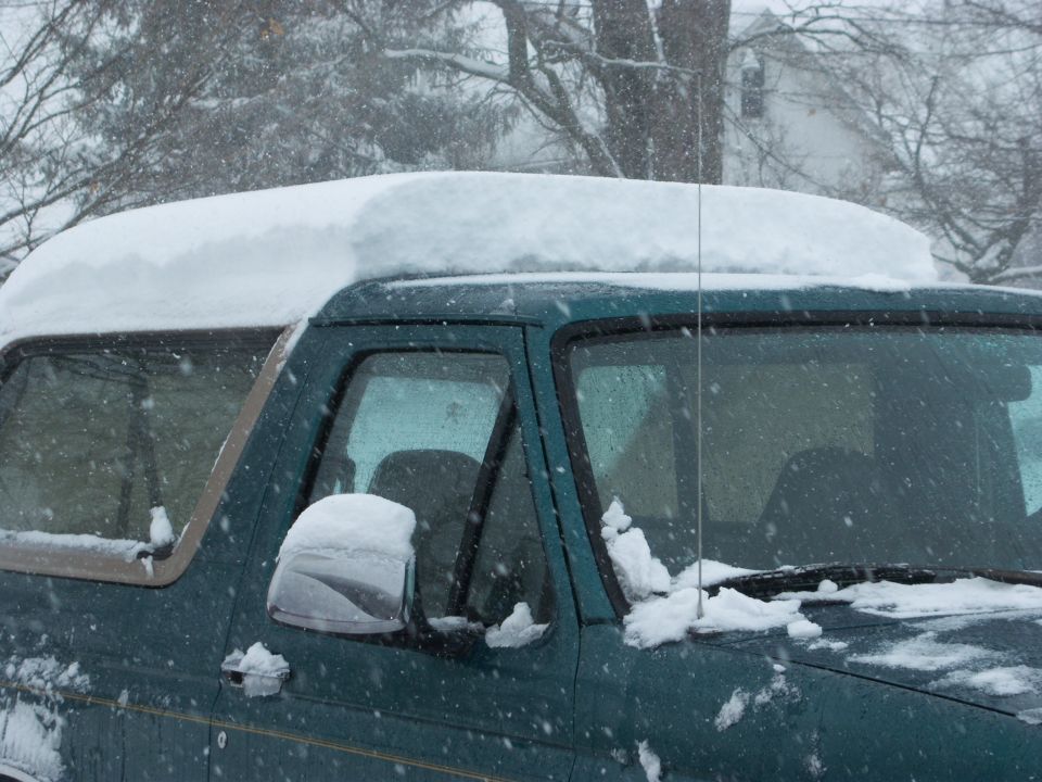 1996 Ford Bronco with snow on the roof and windshield during a snowfall